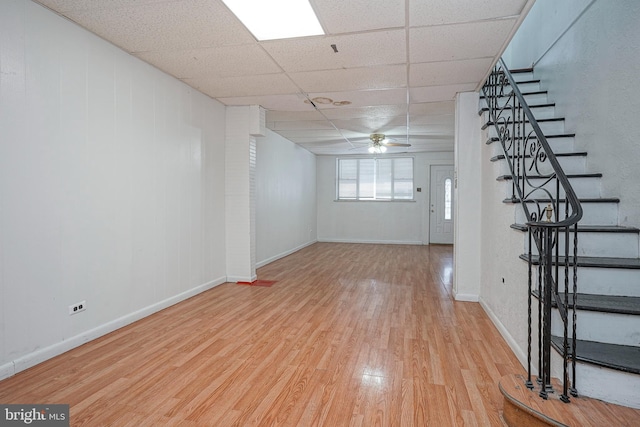 interior space with light wood-type flooring, a drop ceiling, and ceiling fan