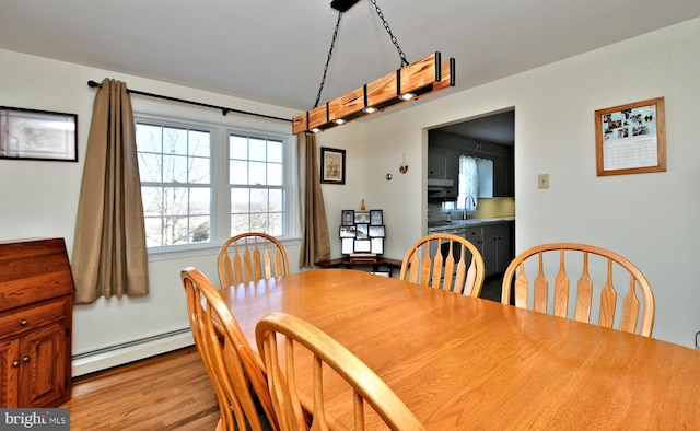 dining room featuring light hardwood / wood-style flooring, a baseboard heating unit, and sink