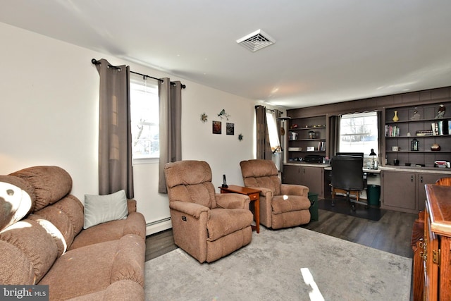 living room featuring hardwood / wood-style flooring, a healthy amount of sunlight, and a baseboard heating unit