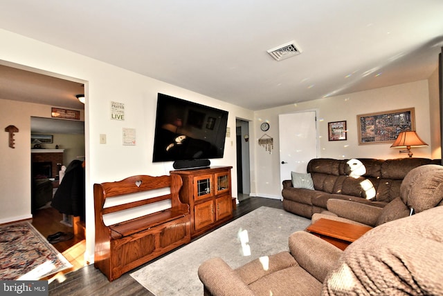 living room with dark wood-type flooring and a brick fireplace