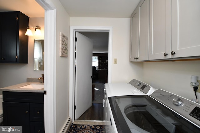 clothes washing area with cabinets, independent washer and dryer, sink, and a baseboard heating unit