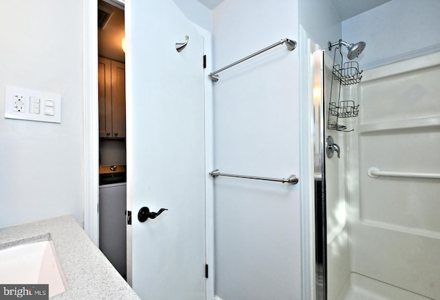 bathroom featuring a shower, vanity, and washer / dryer