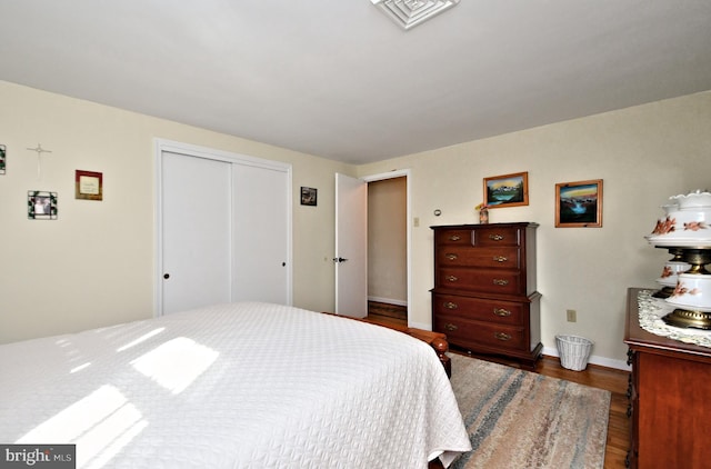 bedroom with dark hardwood / wood-style flooring and a closet