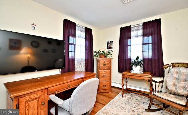 office with baseboard heating, plenty of natural light, and light wood-type flooring