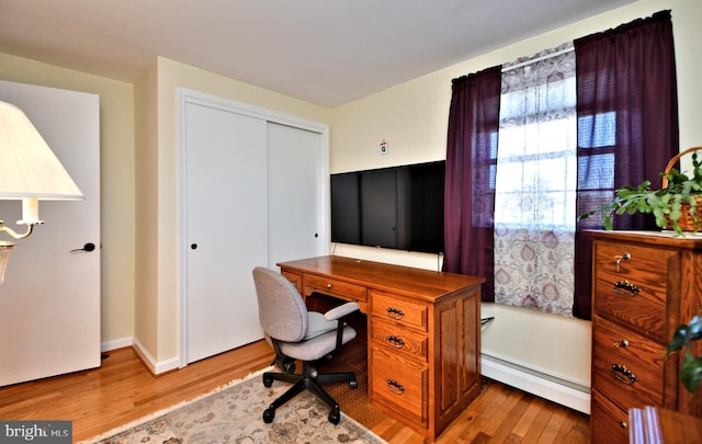 home office with light hardwood / wood-style floors and baseboard heating