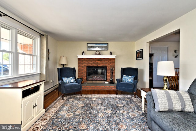 living room featuring wood-type flooring, a baseboard radiator, and a brick fireplace