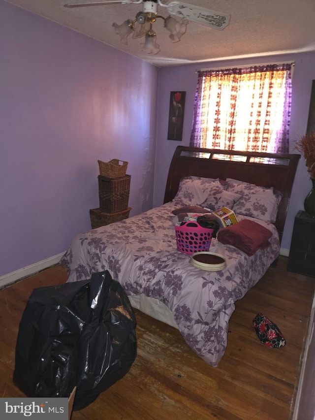 bedroom featuring hardwood / wood-style floors, a textured ceiling, and ceiling fan