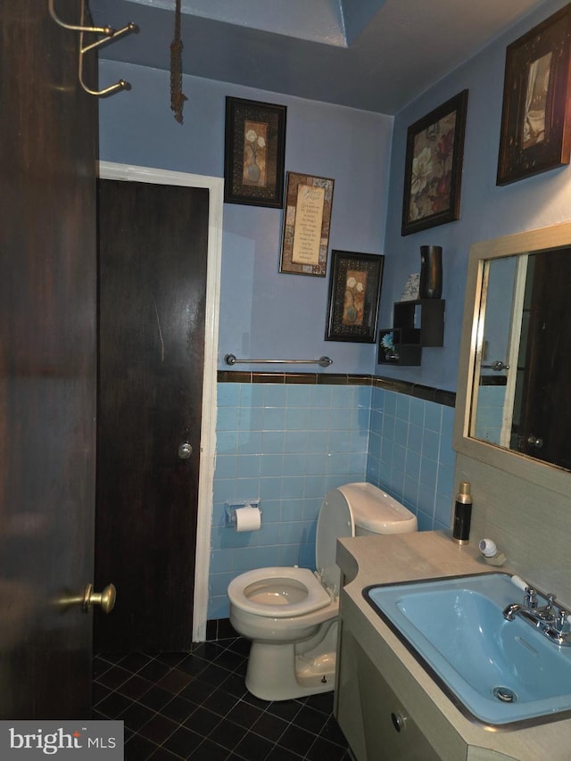 bathroom featuring tile patterned flooring, vanity, toilet, and tile walls