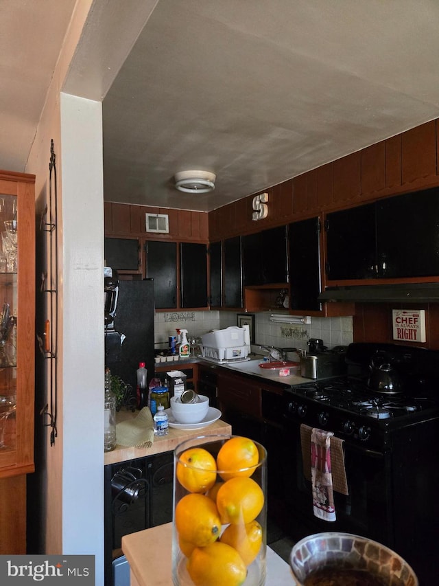 kitchen featuring sink, tasteful backsplash, dark brown cabinetry, and black appliances