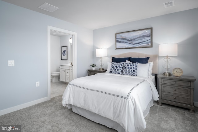 bedroom featuring ensuite bath and light colored carpet