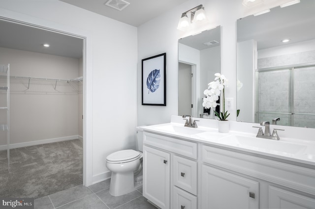 bathroom featuring tile patterned flooring, vanity, toilet, and a shower with shower door