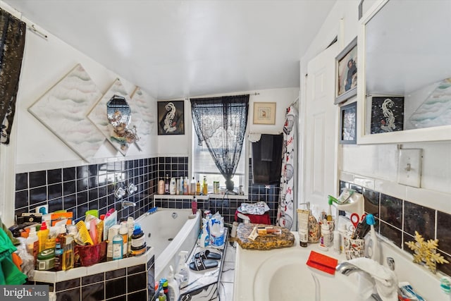 bathroom with tiled bath, sink, and tile walls