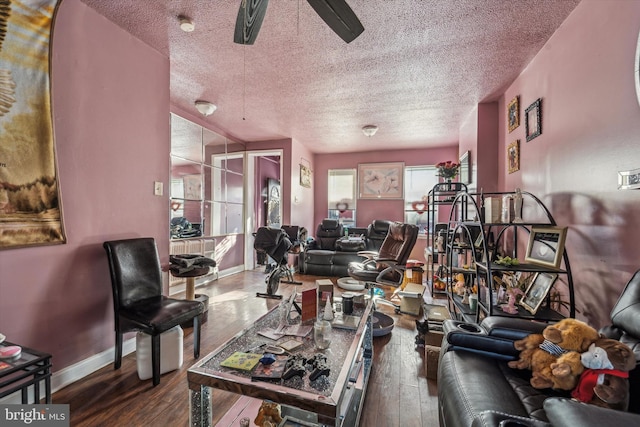 living room featuring dark hardwood / wood-style flooring, ceiling fan, and a textured ceiling