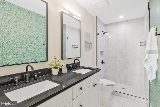 bathroom with tiled shower, vanity, and toilet