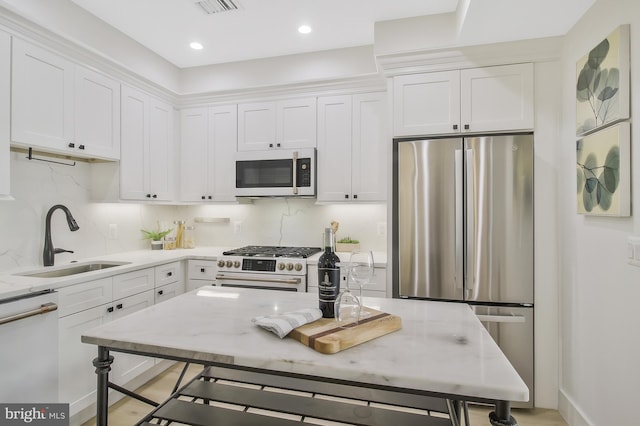 kitchen featuring light stone counters, sink, white cabinetry, and stainless steel appliances