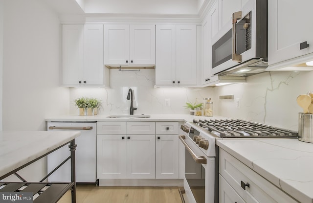 kitchen featuring white appliances, sink, decorative backsplash, light stone counters, and white cabinetry