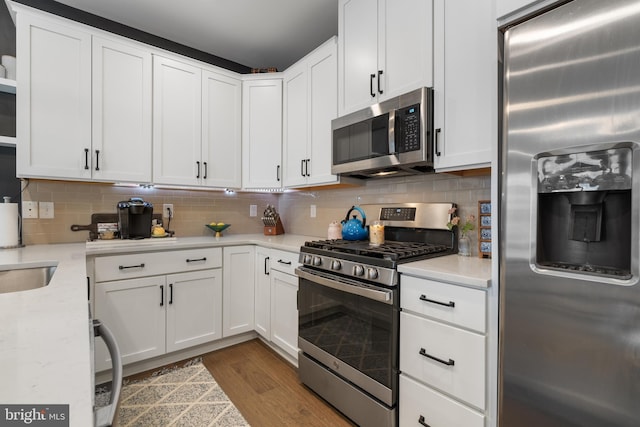 kitchen with white cabinets, backsplash, stainless steel appliances, and light hardwood / wood-style floors