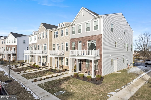 townhome / multi-family property featuring a balcony and a front lawn