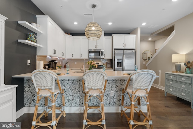 kitchen with white cabinets, pendant lighting, stainless steel appliances, and tasteful backsplash