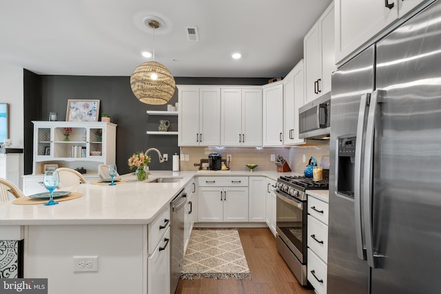 kitchen featuring decorative backsplash, appliances with stainless steel finishes, sink, pendant lighting, and white cabinets