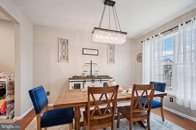 dining area featuring a healthy amount of sunlight, a chandelier, and wood-type flooring