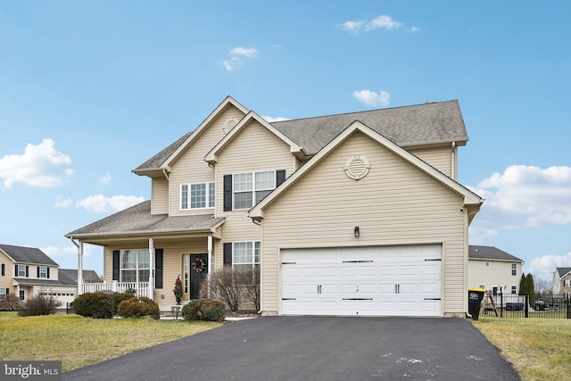 view of front of home with covered porch, a garage, and a front yard