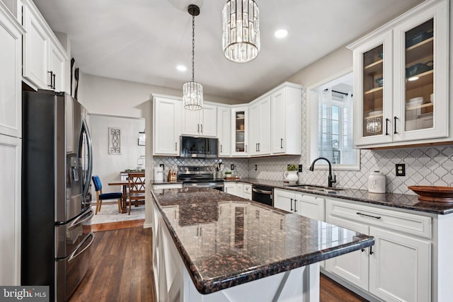 kitchen featuring white cabinets, sink, hanging light fixtures, a kitchen island, and stainless steel appliances