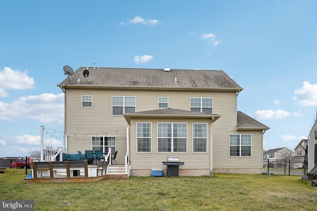 back of property featuring a deck and a lawn