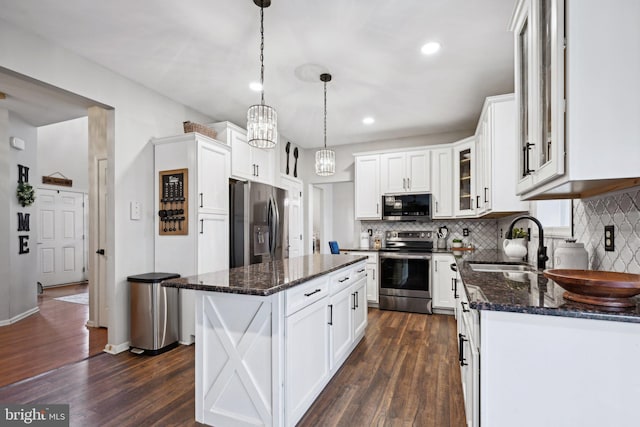 kitchen with a center island, sink, stainless steel appliances, pendant lighting, and white cabinets