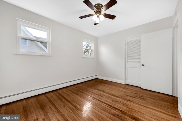 interior space with wood-type flooring, a closet, ceiling fan, and a baseboard heating unit