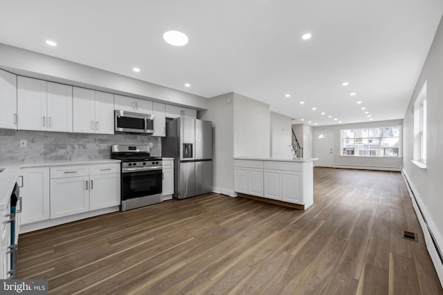 kitchen with backsplash, a baseboard radiator, dark hardwood / wood-style flooring, white cabinetry, and stainless steel appliances