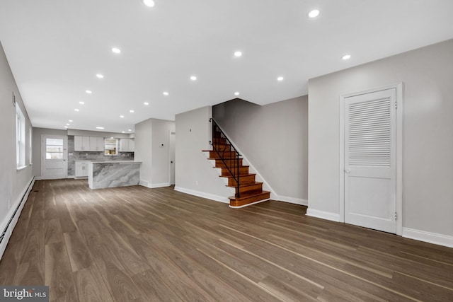 unfurnished living room featuring baseboard heating and dark wood-type flooring