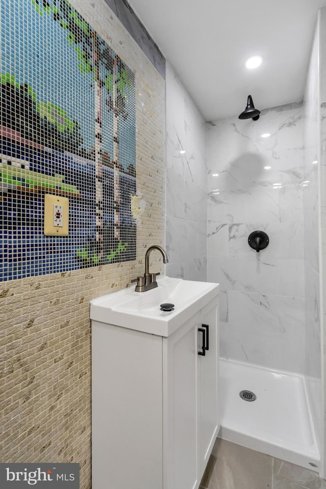 bathroom with vanity, tiled shower, and tile walls