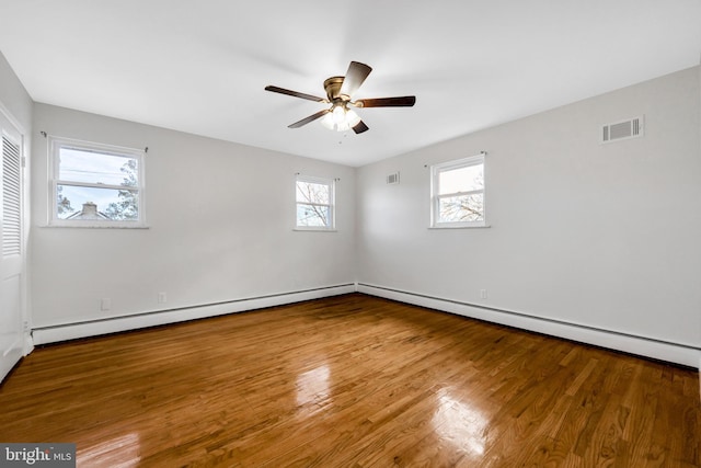 spare room with hardwood / wood-style flooring, ceiling fan, and a baseboard heating unit