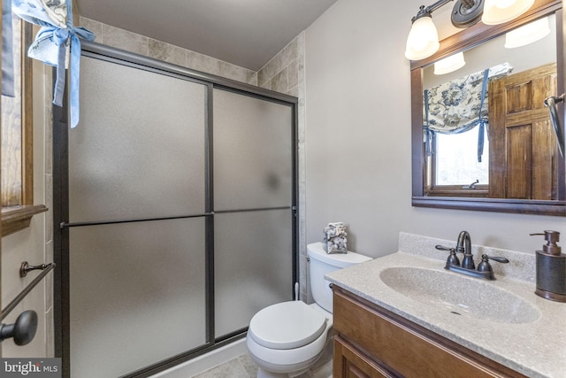 bathroom featuring vanity, toilet, and a shower with shower door