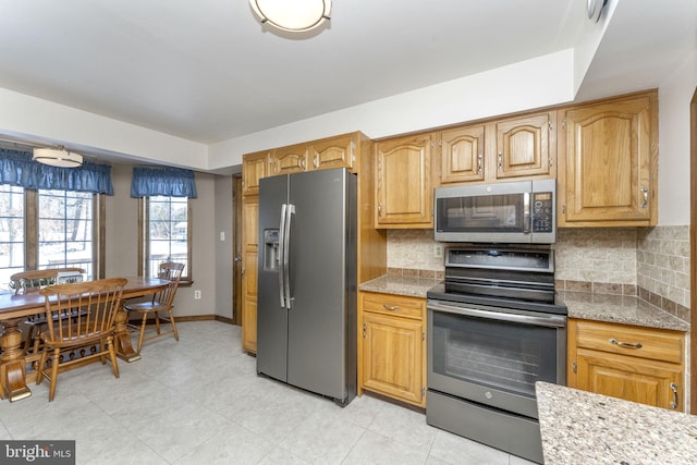 kitchen featuring decorative backsplash, stainless steel appliances, and light stone counters