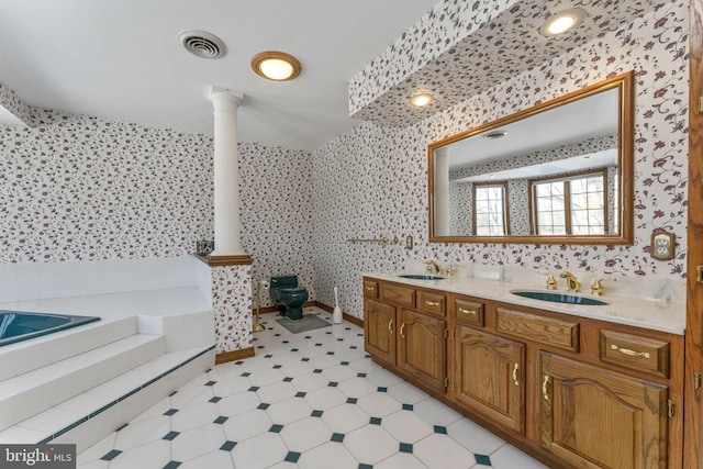 bathroom featuring tile patterned flooring, vanity, a tub to relax in, and ornate columns