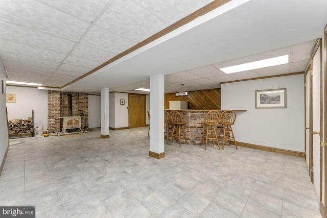 basement featuring a wood stove, bar, and wooden walls