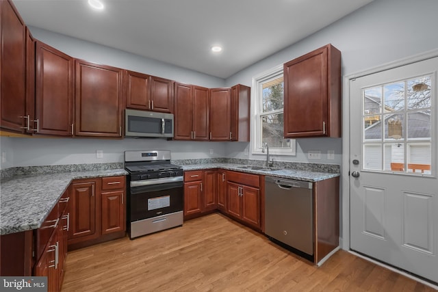 kitchen with stainless steel appliances, light hardwood / wood-style flooring, a healthy amount of sunlight, and sink