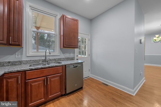 kitchen with stainless steel dishwasher, sink, light hardwood / wood-style flooring, an inviting chandelier, and dark stone countertops