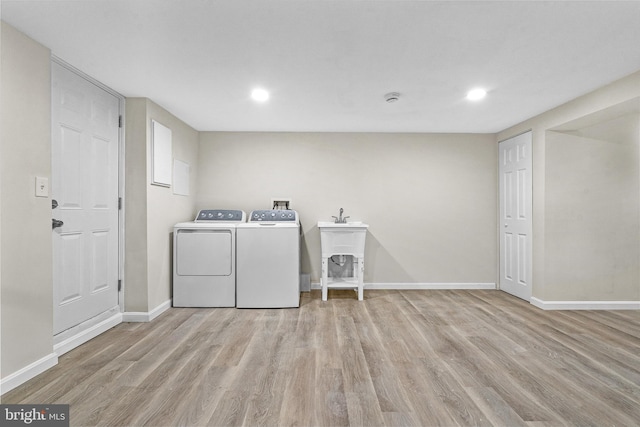 laundry area with washer and clothes dryer, light wood-type flooring, and sink