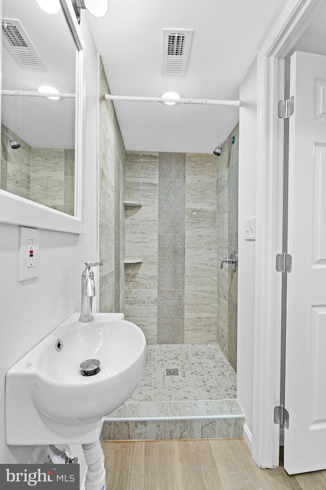 bathroom with a tile shower, sink, and hardwood / wood-style floors