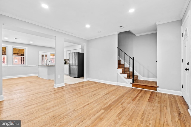 unfurnished living room with light hardwood / wood-style floors, ornamental molding, and sink