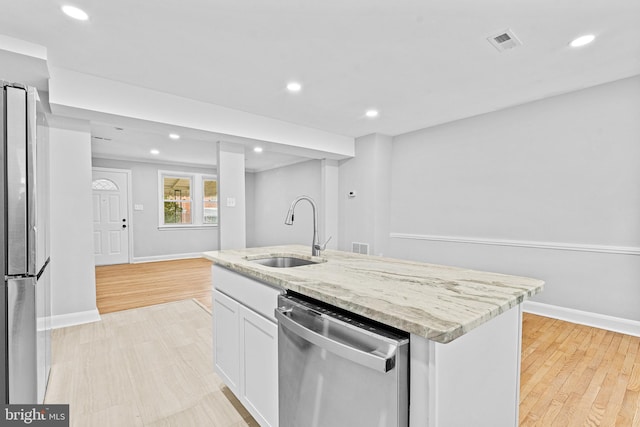 kitchen featuring white cabinetry, sink, light stone counters, an island with sink, and appliances with stainless steel finishes