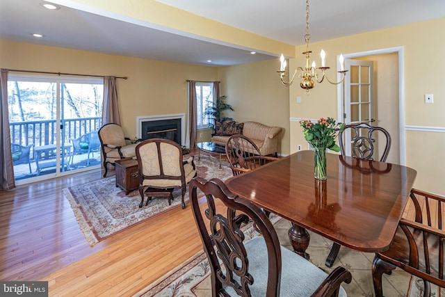 dining area featuring a healthy amount of sunlight, light hardwood / wood-style floors, and an inviting chandelier