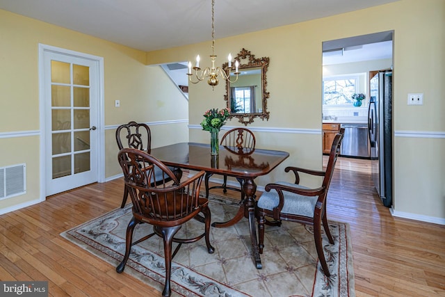 dining area with light hardwood / wood-style floors, an inviting chandelier, and a healthy amount of sunlight