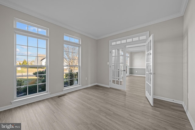 unfurnished room with a healthy amount of sunlight, light wood-type flooring, ornamental molding, and french doors