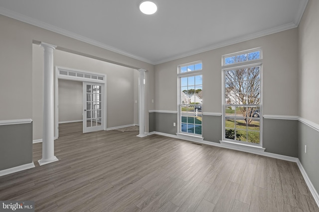 empty room with ornamental molding, hardwood / wood-style flooring, decorative columns, and a healthy amount of sunlight