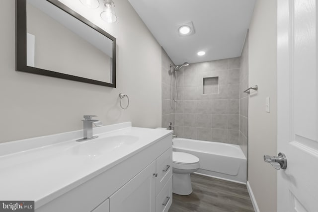 full bathroom featuring vanity, wood-type flooring, tiled shower / bath combo, and toilet