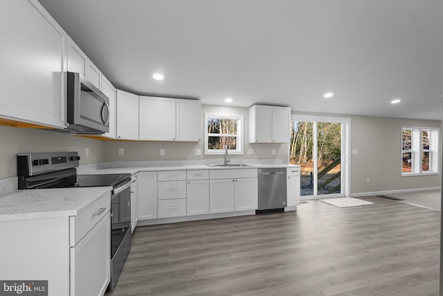 kitchen with sink, white cabinets, stainless steel appliances, and wood-type flooring